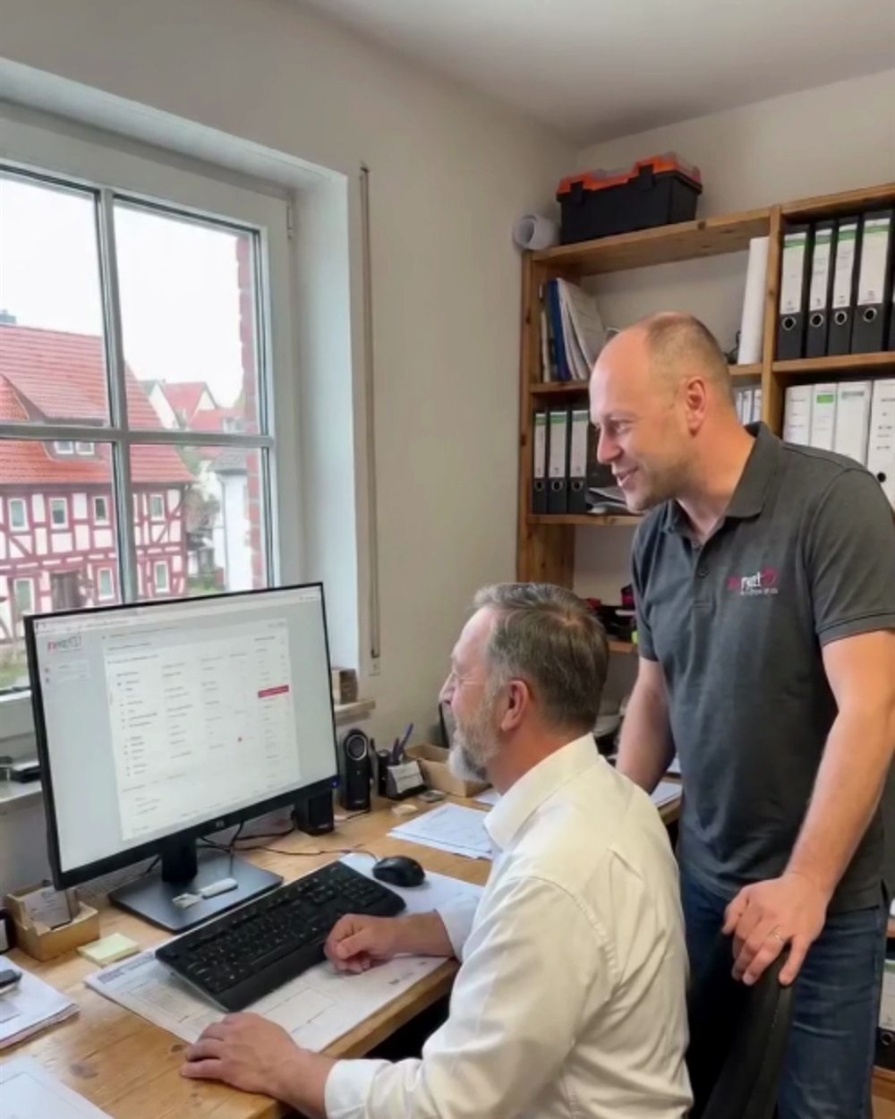 net97 zeigt einem Kunden die maßgeschneiderte Branchensoftware am Bildschirm im Büro